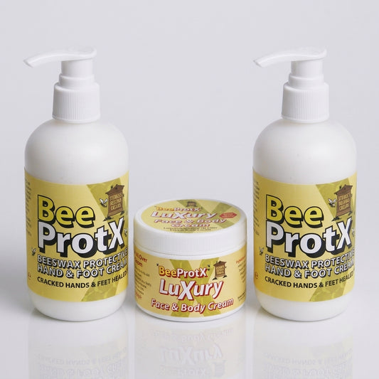 Three BeeProtX skincare products on a light gray reflective background: two white pump bottles and one white jar with yellow labels.