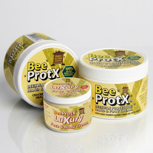 Three tubs of BeeProtX cream arranged on a light gray reflective surface. The products include 2 large tubs of Beeswax Hand & Foot Cream and a smaller tub of Luxury Face & Body Cream.