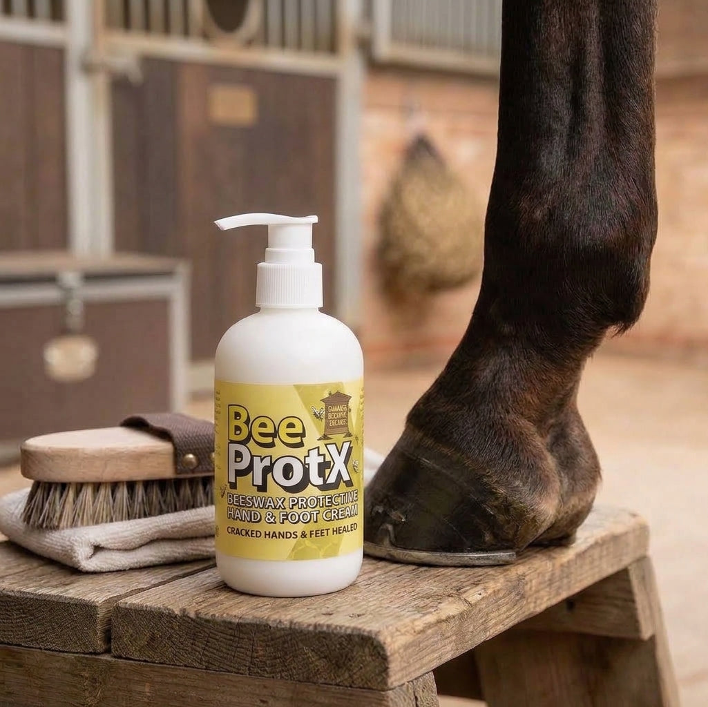 A pumper bottle of BeeProtX Hand & Foot Cream sits on a wooden stable bench next to a horse's lower leg and hoof, with a brush and towel nearby in a stable setting.
