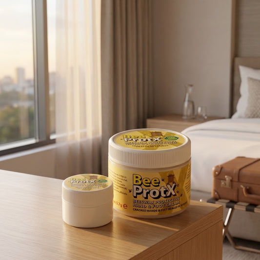 Two tubs of BeeProX Beeswax Barrier Hand & Foot Cream displayed on a wooden table in a modern, sunlit hotel room.