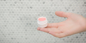 Lip Balms and Salves image featuring a pot of lip balm and a hand